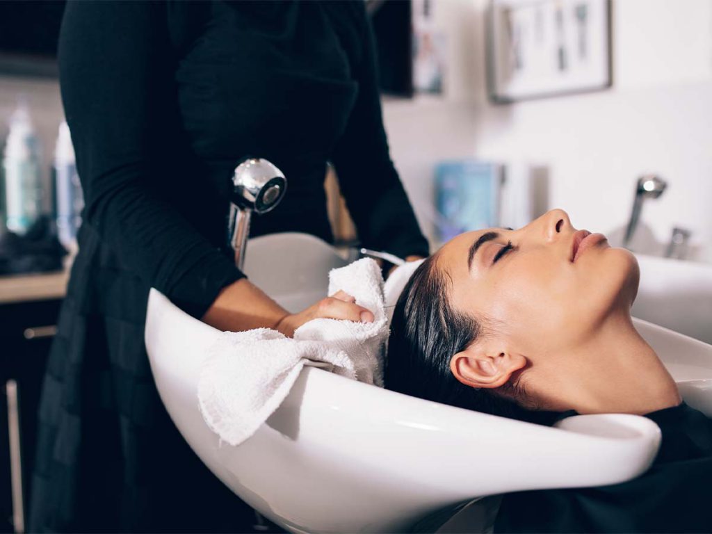 A woman having her hair conditioned at the salon